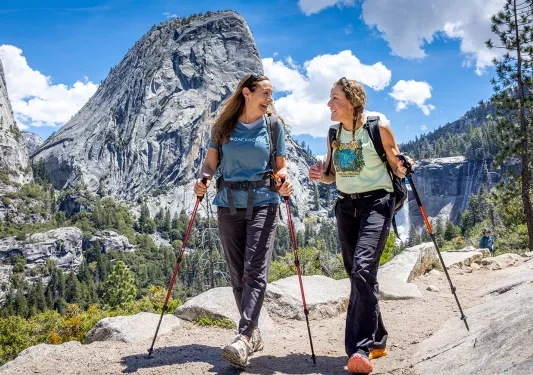two women with hiking poles hike in yosemite