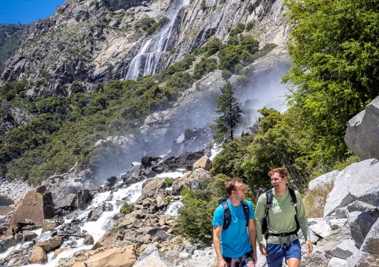 two hikers walk up a rocky trail