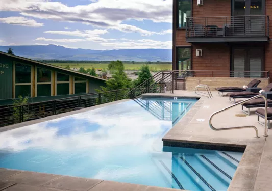 Outdoor infinity pool with a red brick hotel building on the right
