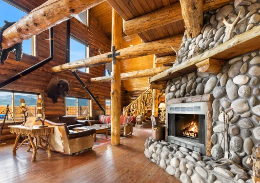 Wooden cabin lobby with giant wooden pillars and a stone fireplace on the right