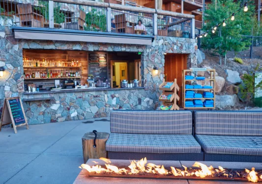 Outdoor bar area with a stone wall and a sofa in front of a stone fire pit