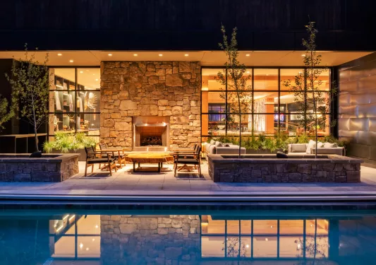 Outdoor lounge next to a pool and a fireplace
