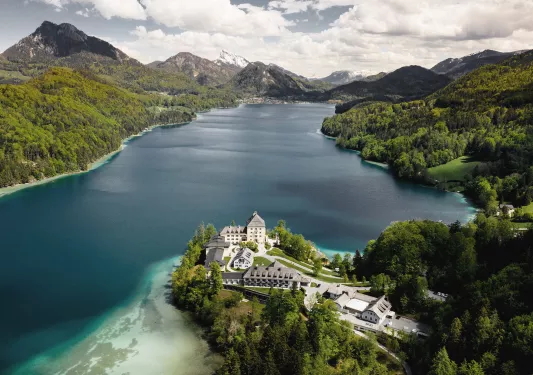 Large blue lake surrounded by mountains with hotel on its shore