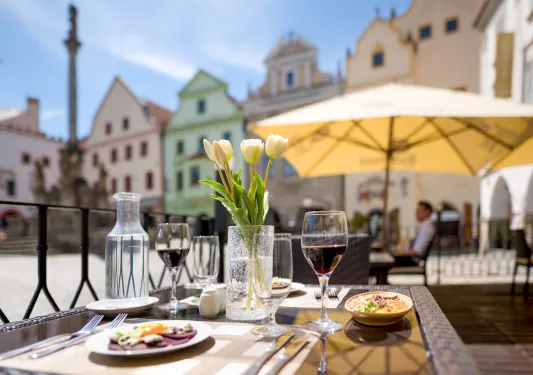 Outdoor dining table with a pot of flowers in the center, and two glasses of wine