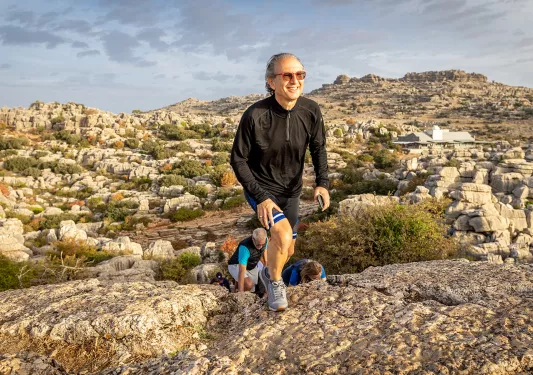 Man ascending a cliff with a large valley in the background