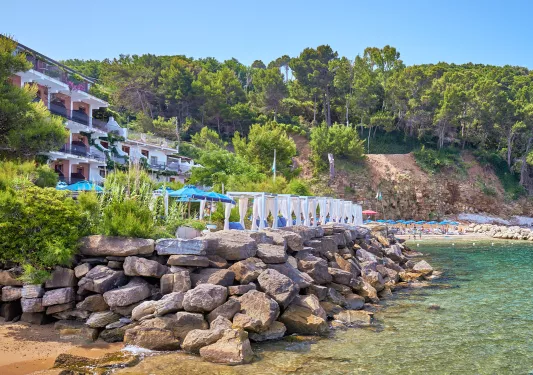 Outdoor patio of a hotel with a stone barricade leading to the ocean