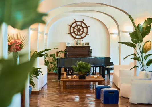 Room with beige couches and a piano in the back