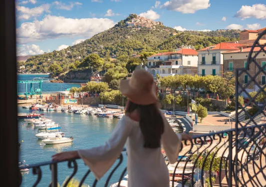 Woman standing on a balcony, looking out towards the ocean