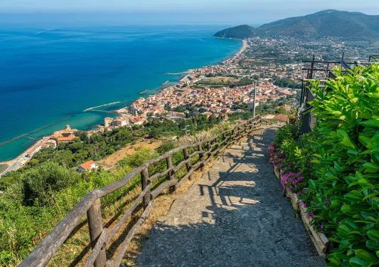Stone staircase on top of a hill, with views of a beach town in the distance