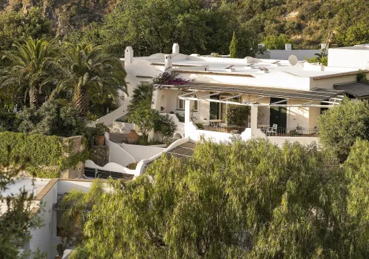 Hotel exterior of a white building surrounded by trees