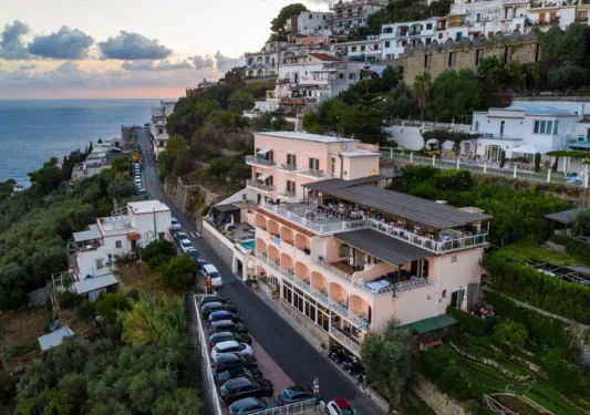 Exterior sky view of a peach-colored hotel building, with a long road in front