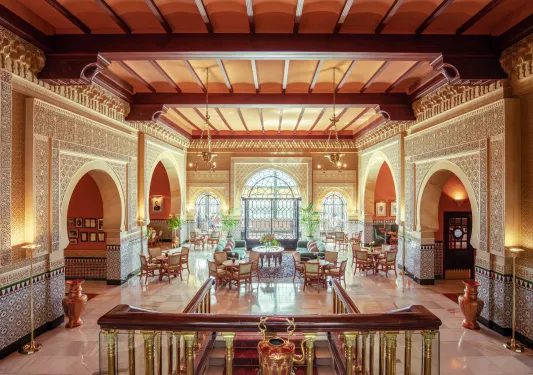 Hotel lobby with a large flight of stairs leading to tables and large windows