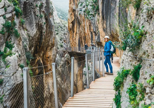 Woman standing on a wooden bridge, between two large cliffs