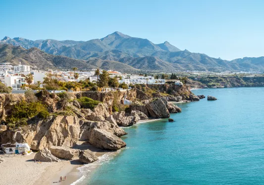 Wide shot view of a town on top of a cliff with the ocean to the right