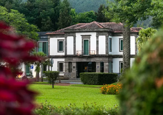Exterior view of white and brown stone building with a grass field in front