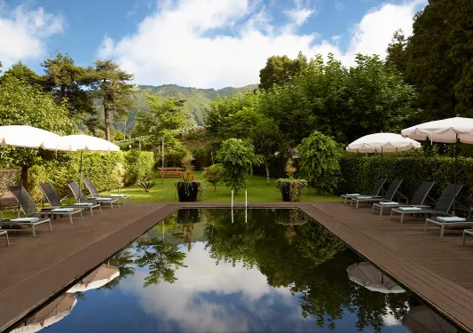 Outdoor pool with wooden walkways and a garden in the background