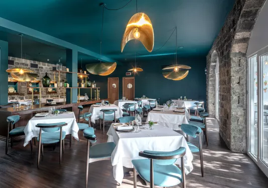 Dining hall with square, white tables and teal chairs