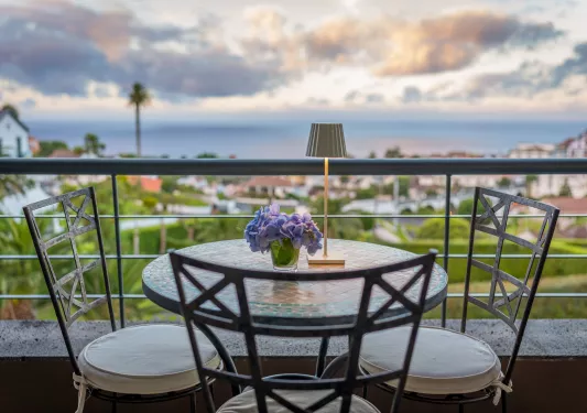 Outdoor balcony with a small circular table and 3 stools