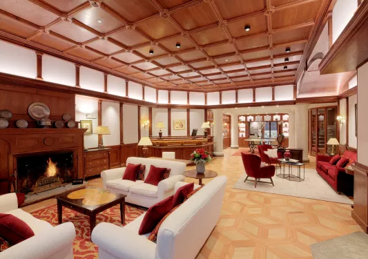 Hotel lobb with wooden ceilings and white walls, with white sofas and red pillows