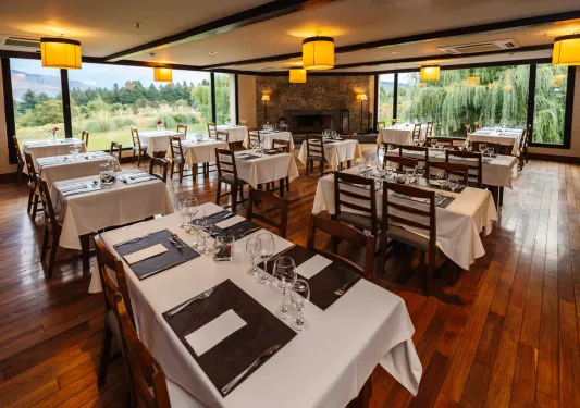 Indoor dining hall with square, white tables and large windows