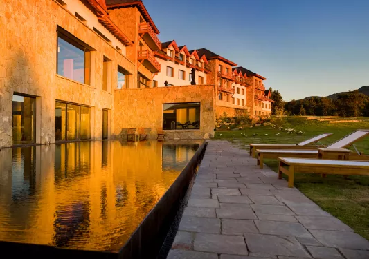 Exterior view of hotel building with an outdoor pool, and large grass area