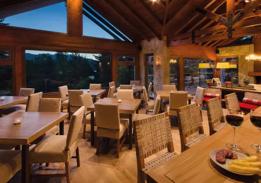 Indoor dining hall of a wooden cabin with wooden tables and chairs