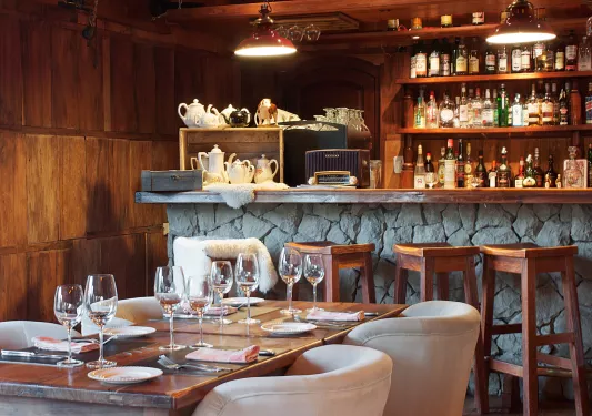 Bar and lounge with a dining table and wine glasses in front