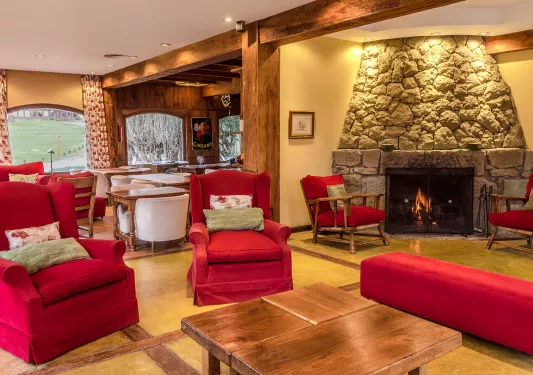 Lounge and seating area, with red cushioned chairs and a stone fireplace