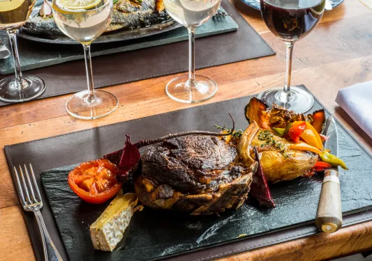 Black plate with roasted meat and vegetables