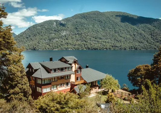 Exterior view of multi-level building with a hills in the background and a lake