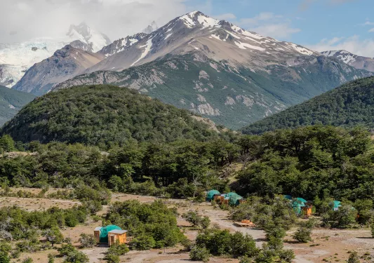 Large valley with small dome huts, and large trees in the background