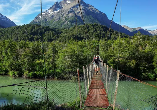 Group of people walking across a suspended, wooden bridge