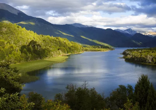 Large, open lake surrounded by tall trees and large hills
