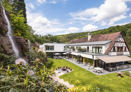 Exterior view of hotel building with an outdoor patio and a small waterfall