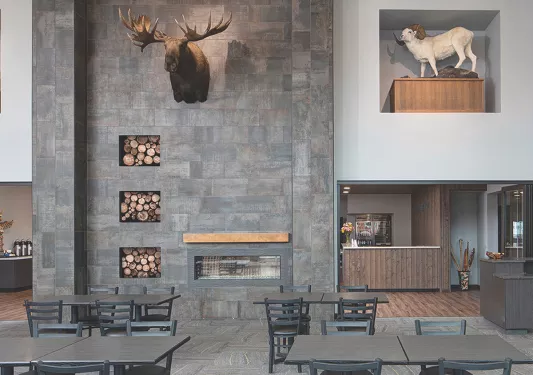 Restaurant dining hall with large stone walls and black dining tables