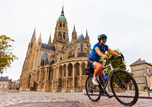Woman riding a bike in front of a large cathedral with stained glass