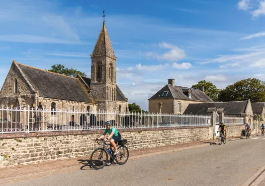 Group of men and women biking on a rod next to a stone church