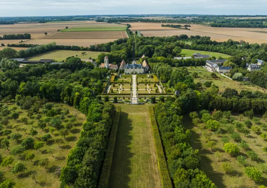 Large grass field and rows of trees surrounding a large white mansion