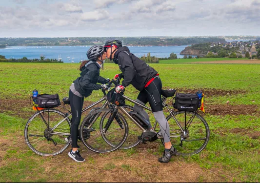 Man and woman standing over their bikes, kissing each other
