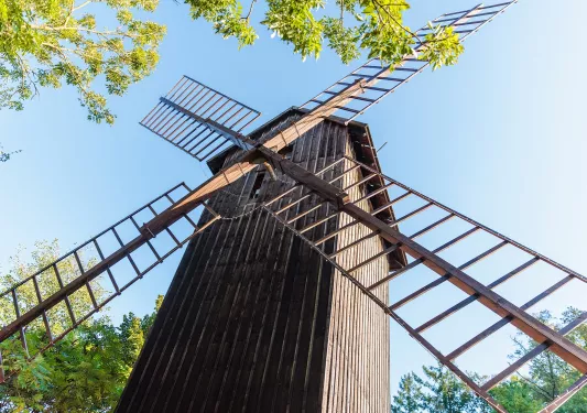 Older, wooden windmill with trees surrounding it