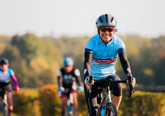 Woman wearing biking gear, smiling while riding a bike