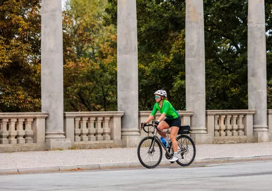 Woman in a green shirt, riding a bike on a road
