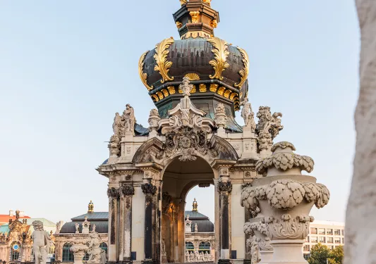White, green and gold palace-like structure with larger buildings in the background