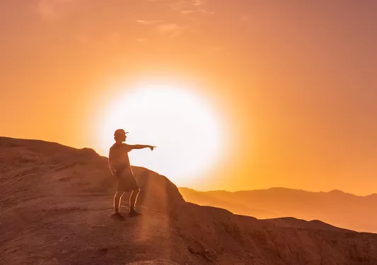 Person standing on a cliff with the sunset in the background