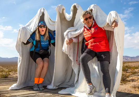 Two women standing inside tall, clay statues