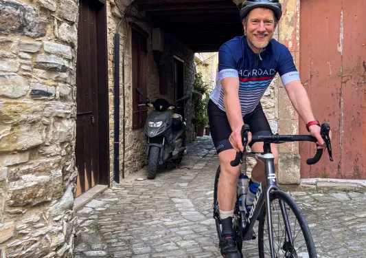 Man smiling while riding a bike through a stone alleyway