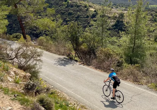 Person riding bike on an empty road, surrounded by a large valley