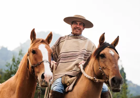 Man wearing a poncho riding a horse