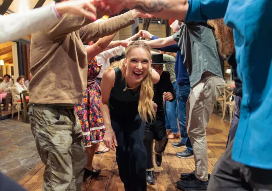 Woman walking under a group of people with their arms sticking out