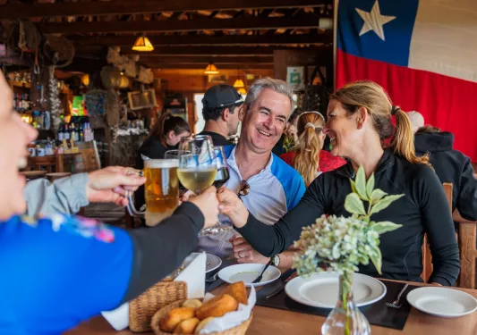 Man and woman smiling at each other at a dining table, while raising their glasses of drinks